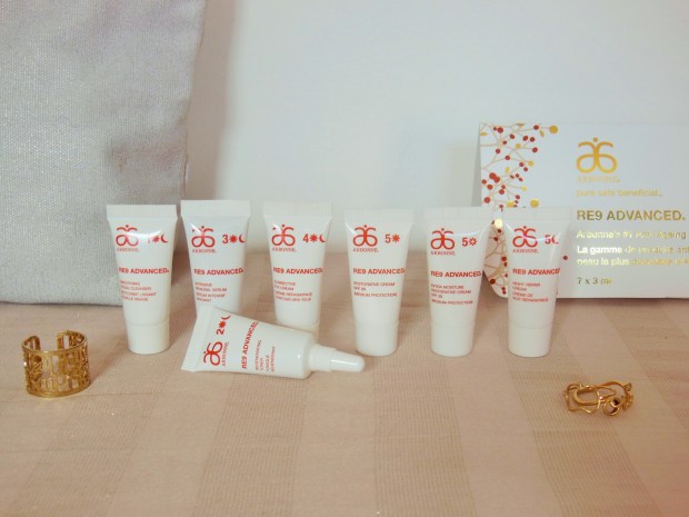 Arbonne RE9 Advanced skincare mini tubes in a row on a beige background