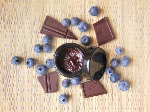 Black pot of skincare with dark chocolate and blueberries