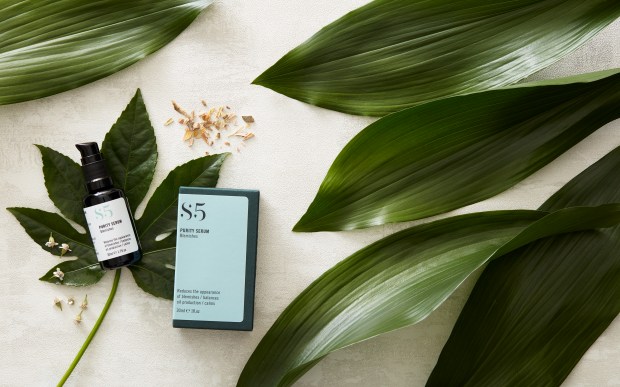 Bottle of serum and box on green leaves