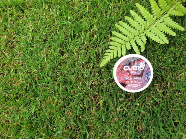 Mini pot of hand cream on grass background