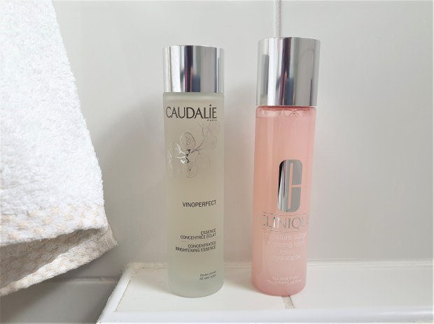 Two skincare bottles in a white bathroom